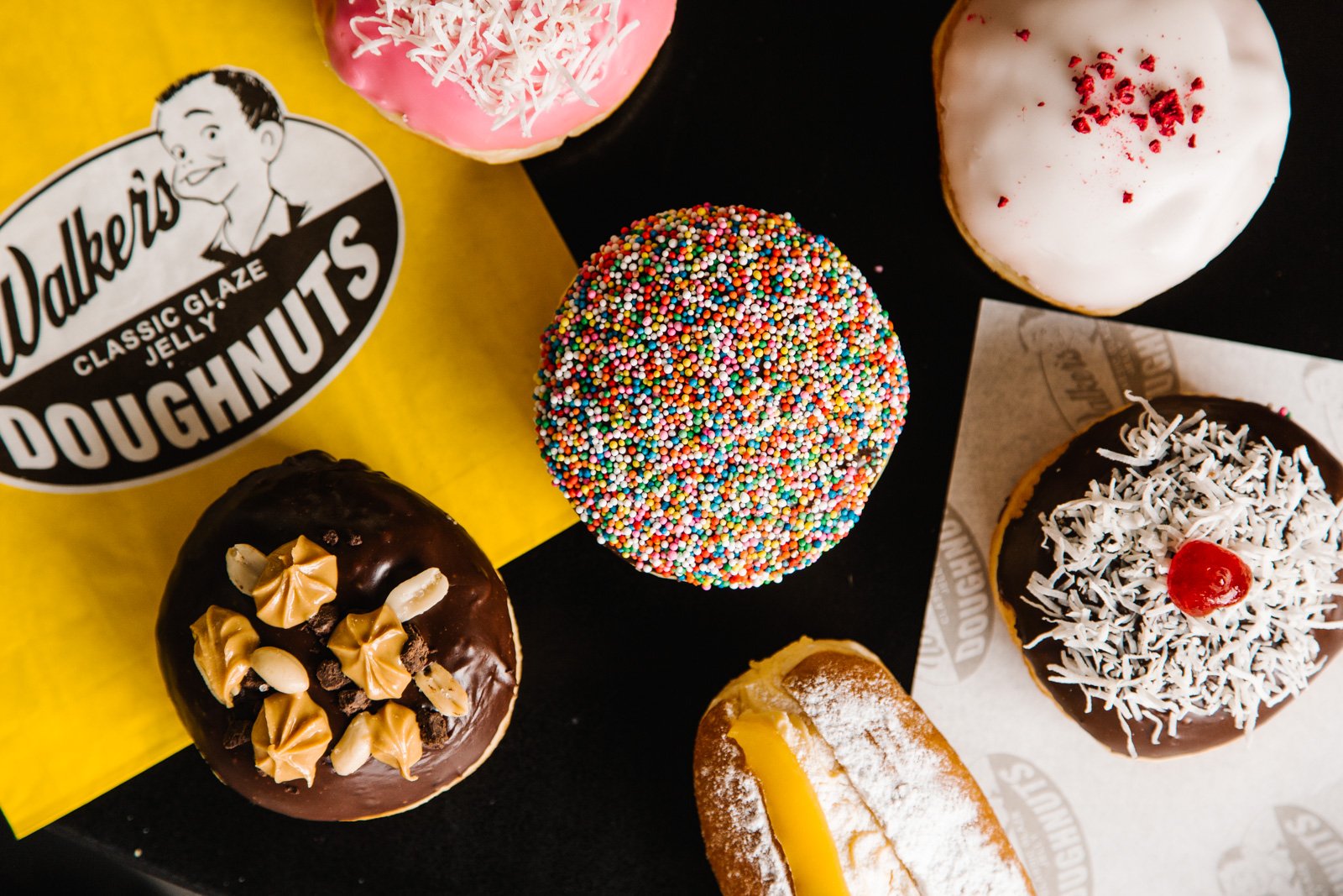 Flat lay of assorted Walker's Doughnuts with the yellow box